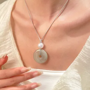 Dettaglio del pendente ad anello in finta giada verde con perla su cordoncino grigio