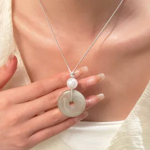 Dettaglio del ciondolo ad anello in finta giada con perla bianca su cordino grigio