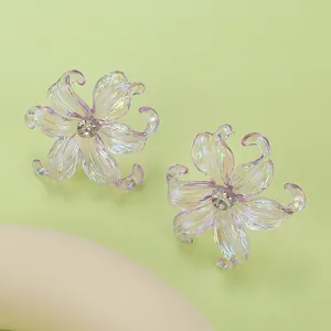 Macro shot of iridescent y2k iris flower stud earrings with a crystal center on green background