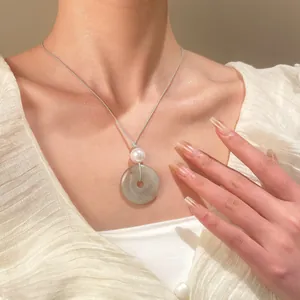 Dettaglio della collana con ciondolo in giada e perla su cordoncino indossata dalla modella