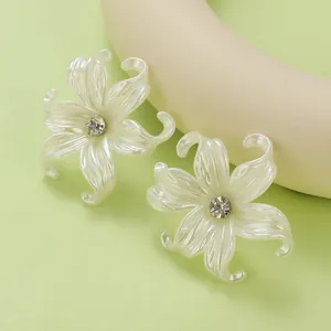 Close-up of pearl white lily flower earrings with sparkling crystals on green background