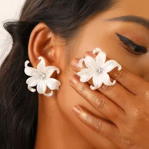Elegant y2k white iris flower earrings with crystal center worn by model in artistic shot