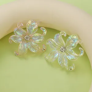 Macro shot of iridescent iris flower earrings with crystal center on a soft green base
