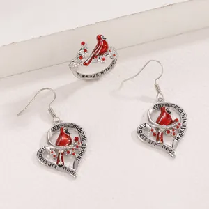 Detailed view of cardinal bird earrings and ring set with heart frame and red enamel