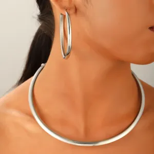 Vue détaillée d'un tour de cou en argent poli et de grandes créoles sur un mannequin