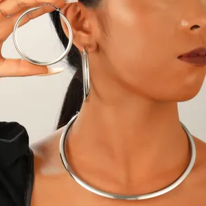 Détail d'une grande boucle d'oreille créole argentée et collier choker en métal assorti