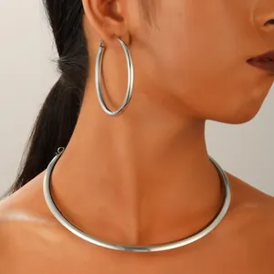 Gros plan sur des créoles en argent minimalistes et un tour de cou en métal pour femme