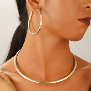 Gros plan d'un collier ras du cou en métal doré et de grandes créoles sur un mannequin