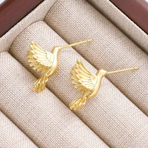 Nahaufnahme goldener Kolibri-Ohrstecker mit matten und polierten Texturdetails