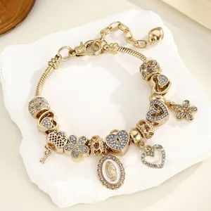 Détails d'un bracelet doré avec perles, pendentif de la Vierge Marie et strass brillants
