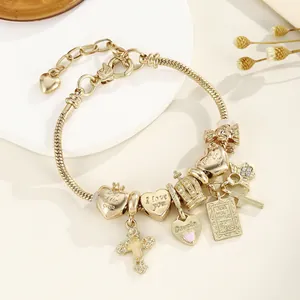 Gros plan d'un bracelet doré à breloques avec croix et cœur gravé sur un plateau blanc