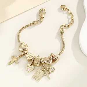 Détail du bracelet chaîne serpent doré avec breloques cœur, couronne et bible