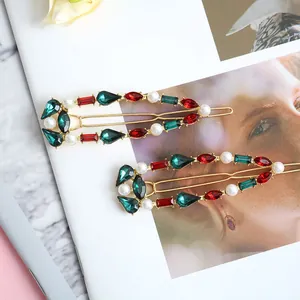 Vintage gold hair clips set with green and red rhinestones and white pearls on magazine