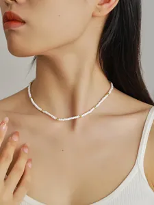 Detalle de las cuentas blancas y espaciadores dorados en el elegante collar de cuentas