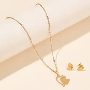 Detail shot of a golden stainless steel butterfly necklace and stud earrings set on a pedestal