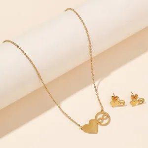Close-up of gold heart and infinity symbol necklace and earring set on white pedestal