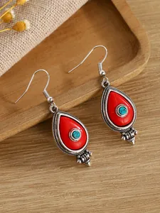 Detail of bohemian teardrop earrings with red stone and turquoise bead on wood