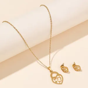 Detail of gold-tone necklace and stud earrings set with hollow heart and bear charm design