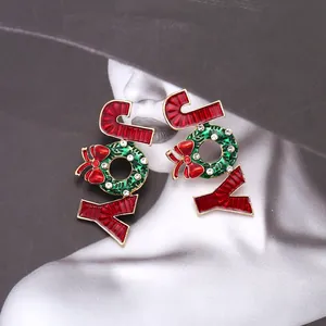 Détail de la broche de Noël JOY avec nœud rouge et motif de couronne sur fond de mode