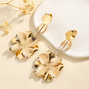 Elegant gold flower tassel earrings with brushed metal petals on minimalist tray