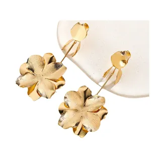 Elegant gold flower tassel earrings with brushed metal texture on white stone background