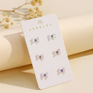 Set van drie paar kleurrijke hars strik-oorstekers op een witte sieraden displaykaart