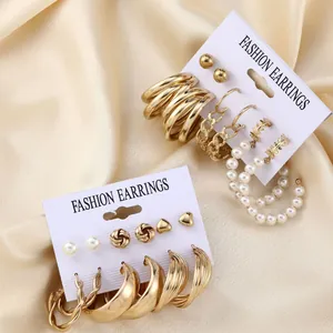 Detailed set of vintage gold hoop earrings and pearl studs on fashion packaging