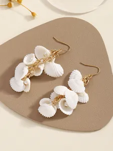 Detalle macro de elegantes pendientes de concha con perlas y cadenas doradas