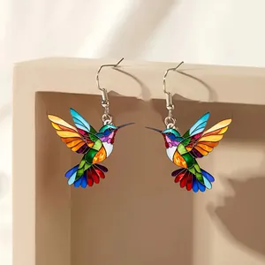 Detailed view of colorful hummingbird drop earrings with vibrant enamel patterns
