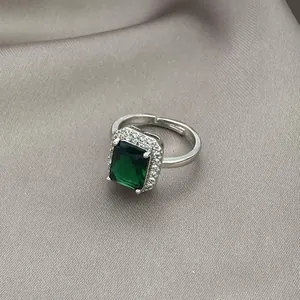 Detailed macro shot of an emerald cut green gemstone ring with halo zircon settings