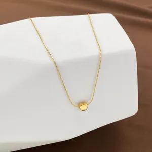 Minimalist gold heart pendant necklace on display stand with polished metallic finish