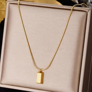 Minimalist gold square pendant necklace with snake chain on champagne gift box