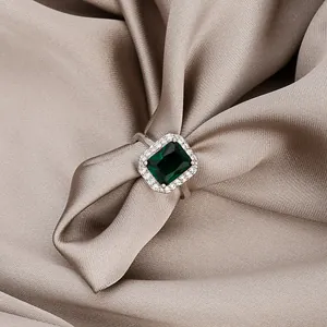 Elegant emerald cut green gemstone ring with white zircon halo on champagne satin