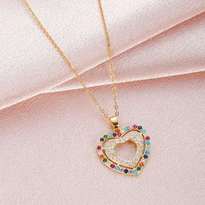 Collar de doble corazón dorado con circonitas de colores sobre satén rosa suave