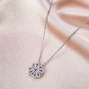 Detail van klavertje vier hanger met hartvormige diamanten op roze zijden textuur