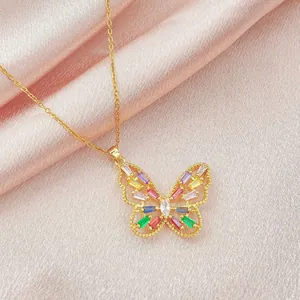 Detalle de collar de mariposa dorado con circonitas de colores sobre seda rosa fina