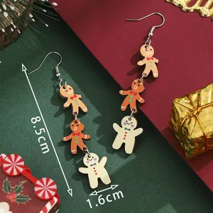 Three-tier gingerbread man drop earrings for Christmas with festive red and green background
