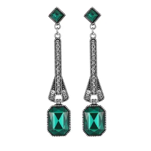 Macro detail of vintage silver drop earrings featuring emerald-cut green gemstones