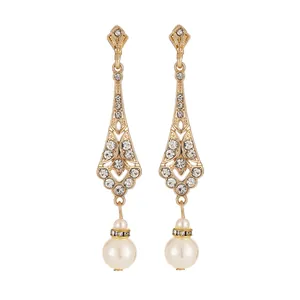 Close-up of gold dangle earrings with sparkling rhinestones and elegant white pearls