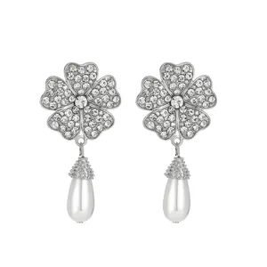 Detailed view of silver flower earrings with pavé crystals and teardrop pearl charms