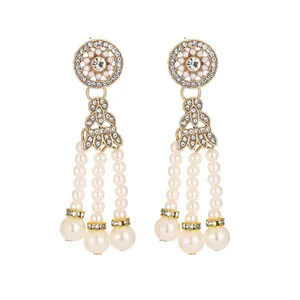 Detail of gold water-drop earrings with white pearl tassels and crystal accents