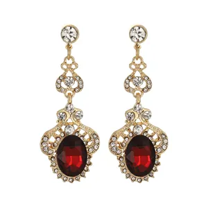 Detail of luxury gold drop earrings with oval red gems and intricate vintage filigree