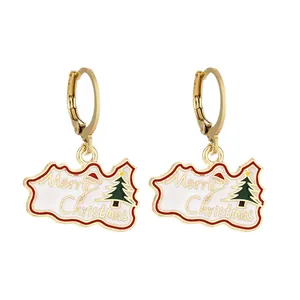 Dettaglio di orecchini natalizi con pendenti in smalto bianco e scritta Merry Christmas