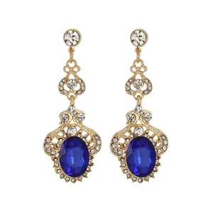 Close-up of vintage gold earrings featuring blue oval gemstones and crystal accents