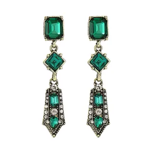 Close-up of vintage drop earrings with green gemstones and rhinestones in bronze finish