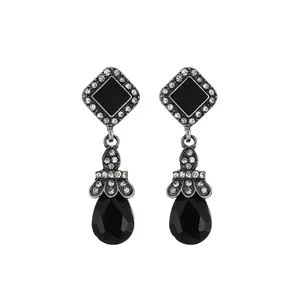 Macro shot of vintage silver earrings featuring black square stones and water drop tassels