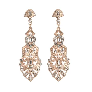 Close-up of rose gold drop earrings with intricate hollow carvings and clear rhinestones