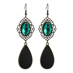 Detail of vintage teardrop earrings featuring green gemstone and matte black drop