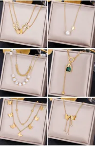 Close-up of gold necklaces with emerald pendants, butterflies, and pearls in jewelry boxes