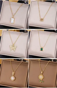 Detailed collection of six gold necklaces with emerald and shell pendants in a jewelry box
